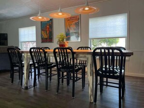 A dining area with a wooden table and black chairs, overhead pendant lighting, and posters on the wall. - Beach Walk Getaway, 1 Block from Oak Street Beach (South Haven)