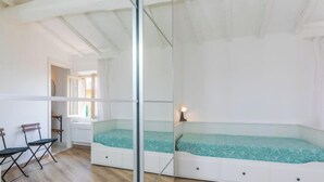 Un dormitori amb un llit superposat, una taula amb una cadira i una finestra amb cortines.