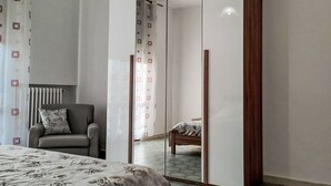 Ein Schlafzimmer mit Bett, Stuhl, Kleiderschrank und Spiegel.