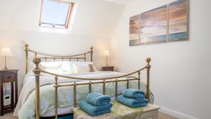 Una camera da letto con un letto, comodini, un tavolo da notte, una finestra e un quadro appeso al muro.