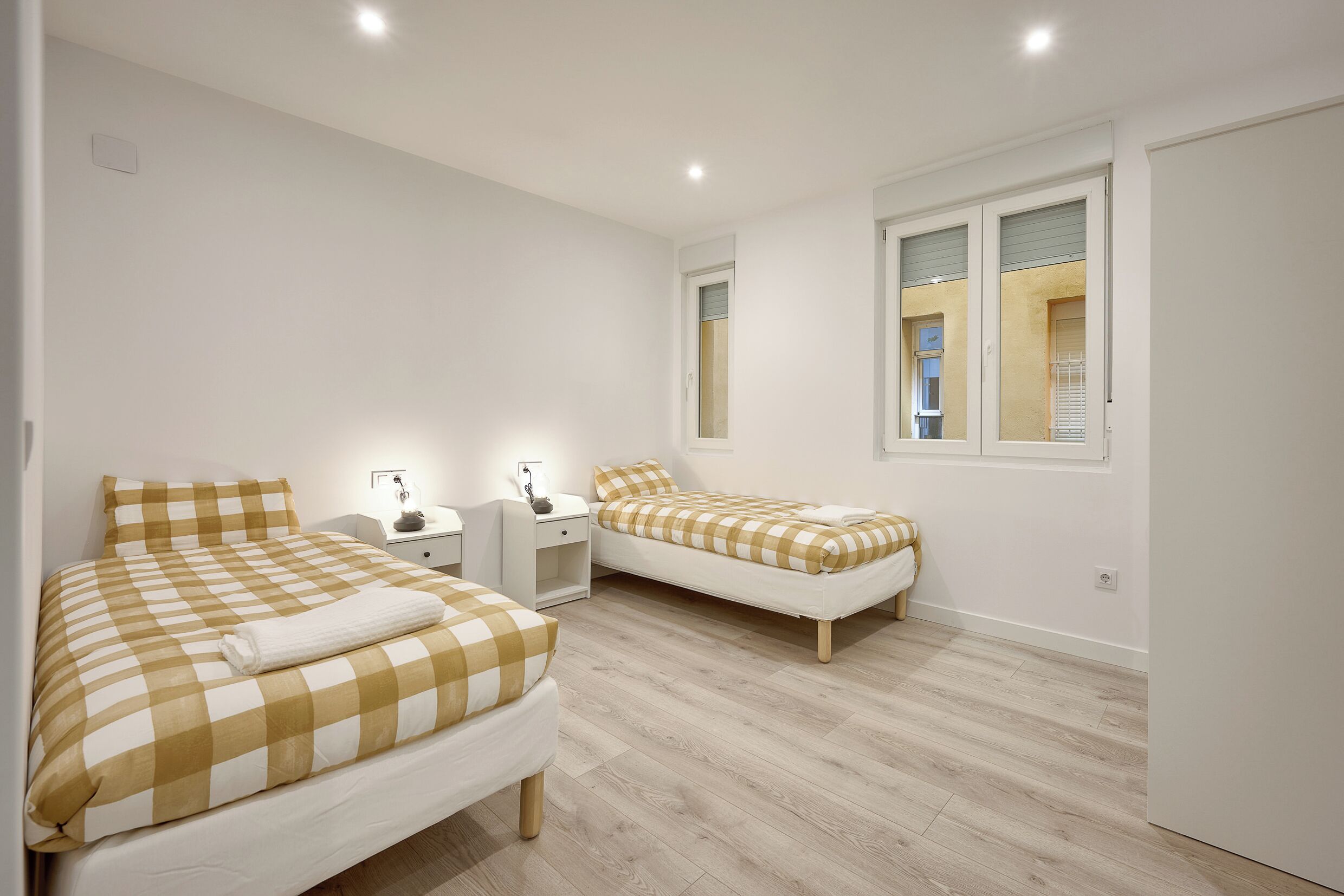 Een slaapkamer met twee bedden, een nachtkastje en een raam.