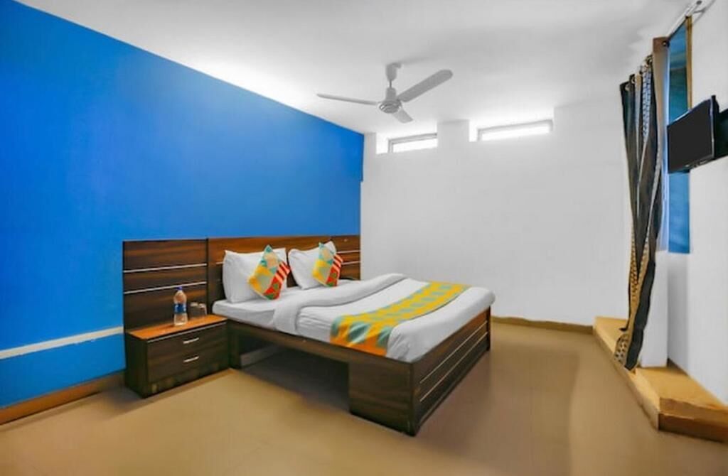 A bedroom with a bed, nightstands, a ceiling fan, and a TV mounted on the wall.