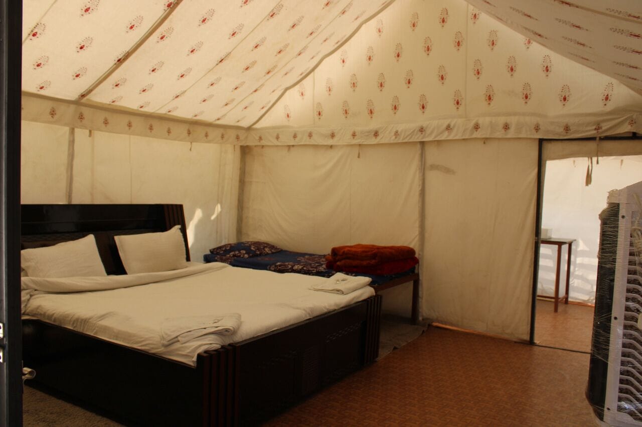 A tented room with a bed, a small table, and a window.