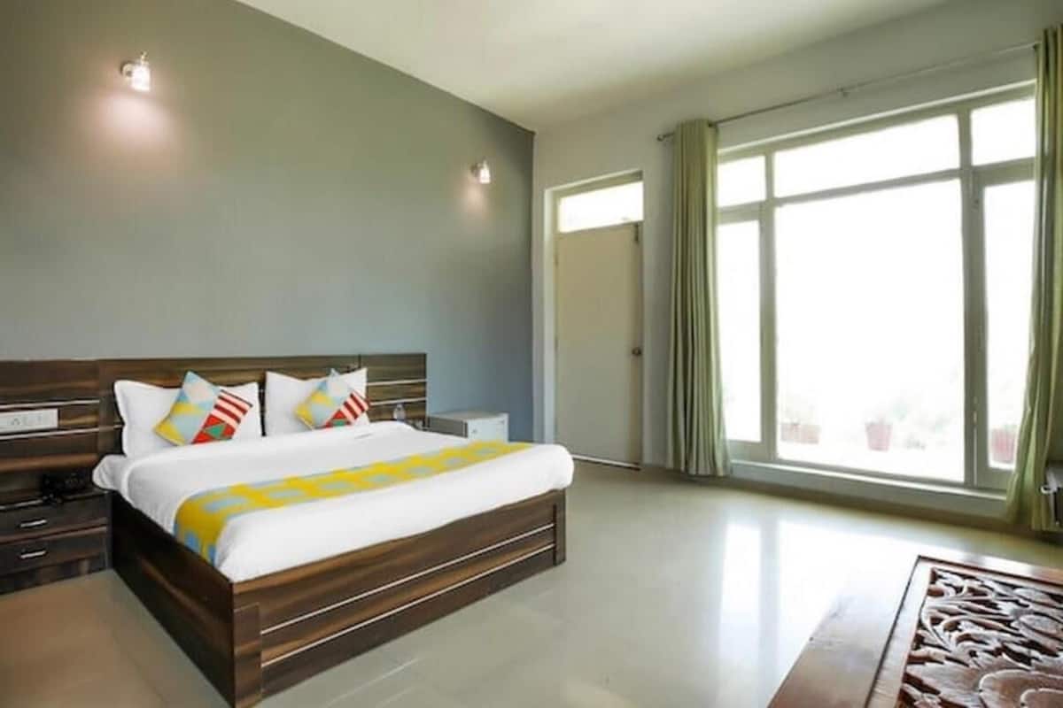 A modern bedroom with a large bed, bedside tables, and a view of the outdoors through a large window.