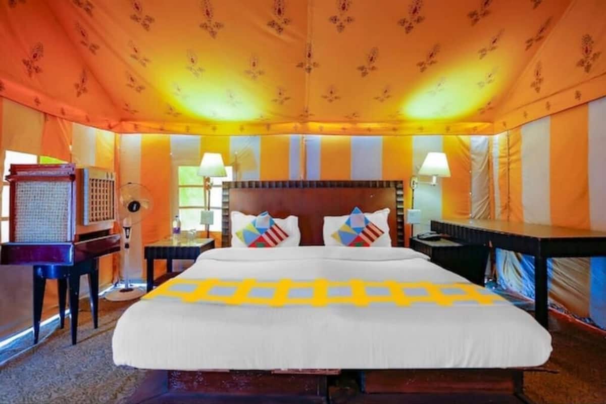 A hotel room with a large bed, two bedside tables, a desk, and a chair.