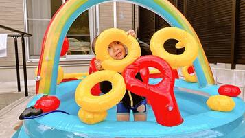 A child in a blue inflatable pool with a rainbow arch and yellow and red rings.