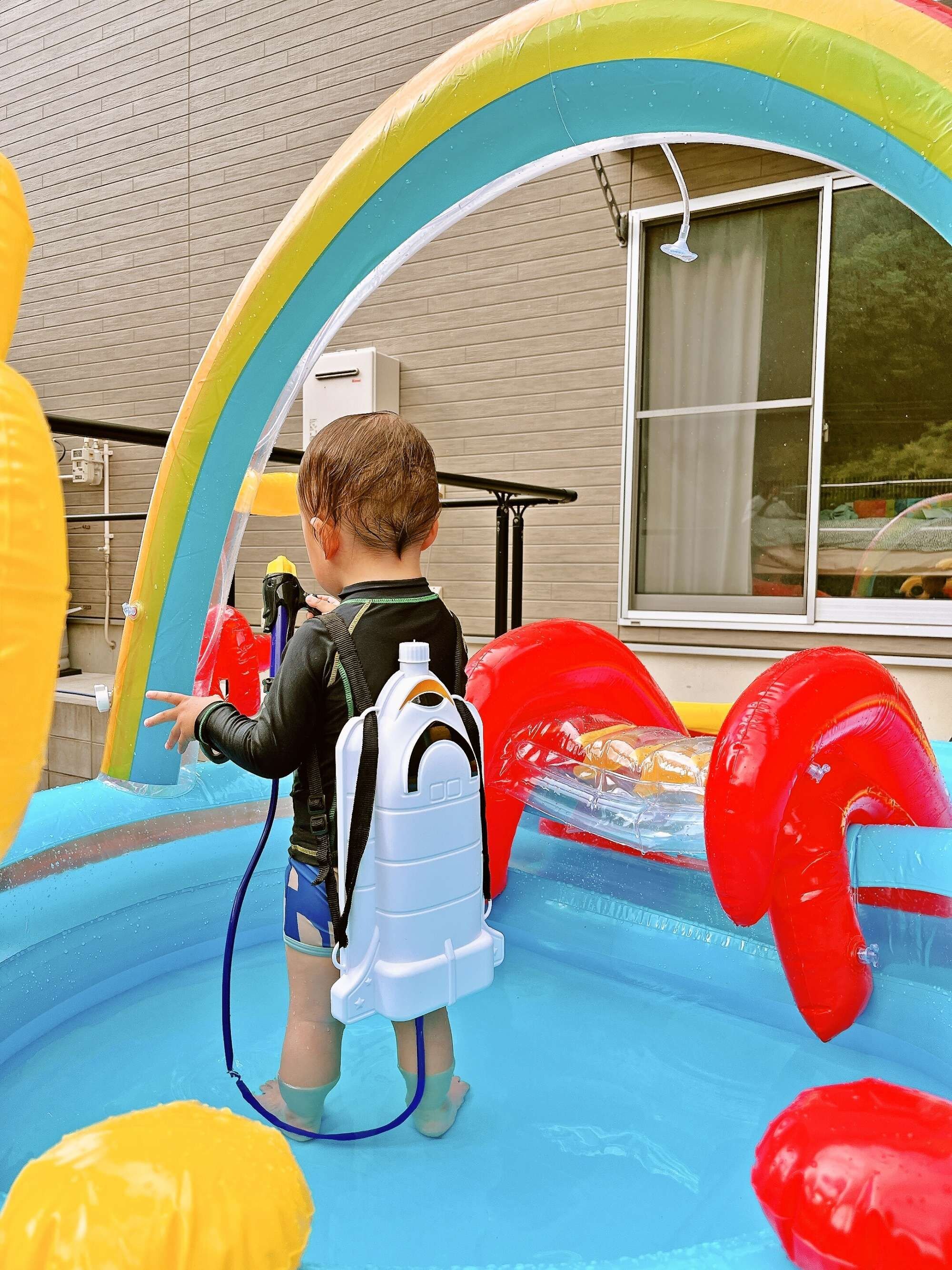 Ein Kind im Pool mit Schwimmspielzeug und einer Wasserpumpe.