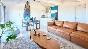 A modern living room with a brown leather sofa, a wooden coffee table, and a dining area with a table set for four.