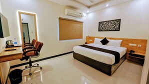 Een hotelkamer met een bed, bureau, stoel en een airconditioning.
