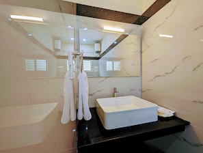 A modern bathroom with a large mirror, a white sink, and a towel rack. - TPC Camphor (Tiruchirappalli)
