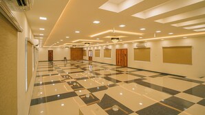Een ruime hotellobby met een zwart-wit schachootvloer, ingebouwde verlichting en een moderne kroonluchter.