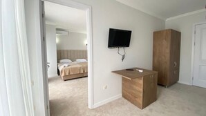 Ein Schlafzimmer mit einem Bett, einem an der Wand montierten Fernseher und einem Holzkasten.