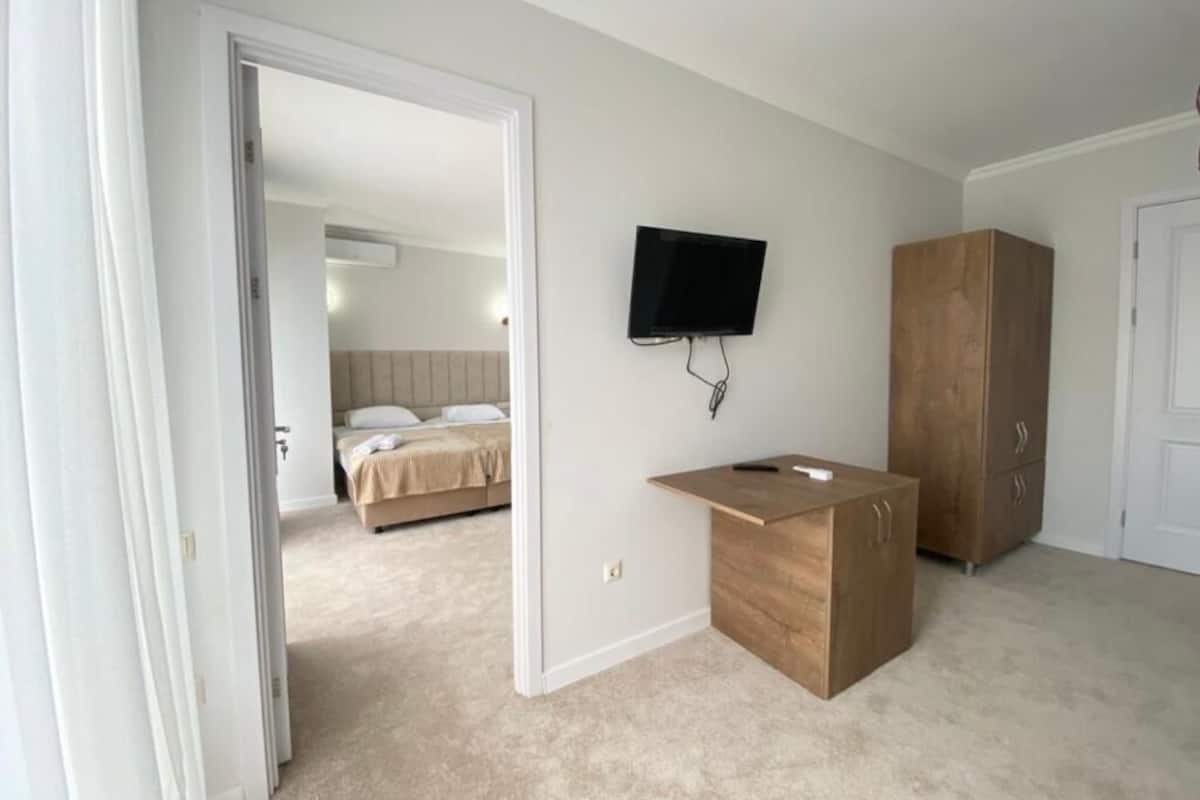 A bedroom with a bed, a TV mounted on the wall, and a wooden cabinet.