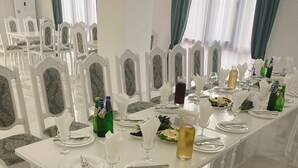 Ein langer Esstisch ist für eine Mahlzeit gedeckt, mit weißen Stühlen, Gläsern und Flaschen.