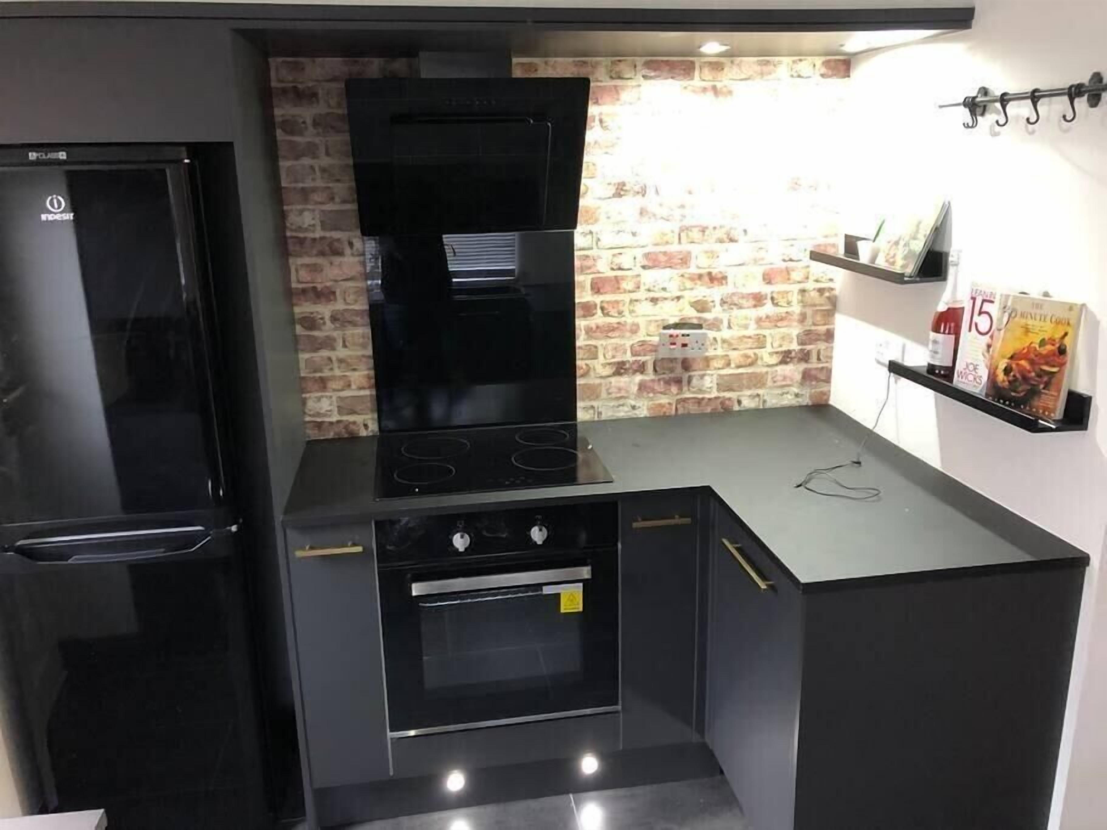 A compact kitchen with a built-in oven, a stove, and a refrigerator.