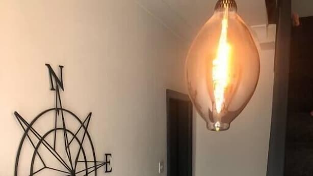 En gang med et kompas som billedkunst og en hængende lysarmatur.