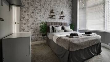 Relax in a stylish bedroom with a large bed, side table, and potted plant.
