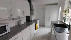 Una cocina moderna con armarios blancos, un microondas y una campana extractora de acero inoxidable.