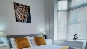 Un dormitorio moderno con una cama grande, un cuadro de un leopardo en la pared y una ventana con persianas.