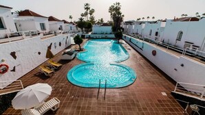 A rooftop swimming pool with tiled flooring, lounge chairs, and umbrellas. - Las Casitas de Corralejo (La Oliva)
