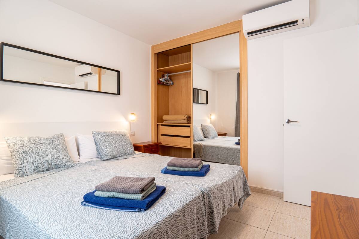 Quarto com cama, guarda-roupa, espelho e ar condicionado.