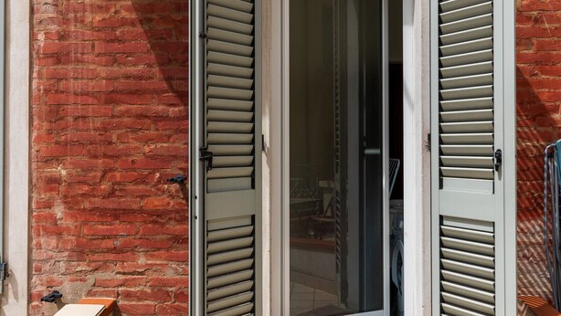 A red brick building with a tiled entrance and a small step leading to a door with shutters. - Studio Calari alle Mura by Wonderful Italy (Bologna)