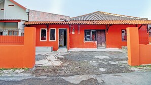 A red building with a tiled roof, a gated entrance, and a visible door. - Hotel O Luqman Kostel Syariah (Semarang)