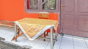A table with a patterned tablecloth outside a building with a red door and a window. - Hotel O Luqman Kostel Syariah (Semarang)