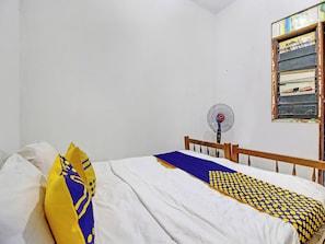 A bedroom with a single bed, a wooden headboard, a wall-mounted fan, and a window with a calendar. - Hotel O Luqman Kostel Syariah (Semarang)