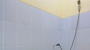 A bathroom with a blue toilet, tiled walls, and a shower area. - Hotel O Luqman Kostel Syariah (Semarang)