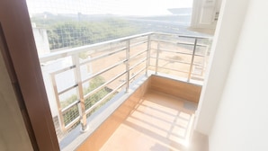 A balcony with a metal railing, a wooden floor, and a view of a cityscape. - DIPLOMAT REGENCY (New Delhi)