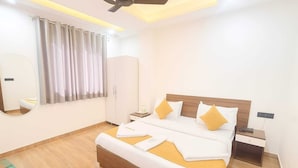 A modern hotel room with a large bed, a bedside table, a nightstand, a mirror, and a wardrobe. - DIPLOMAT REGENCY (New Delhi)