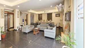 A spacious living area with a sofa set, a coffee table, and potted plants. - DIPLOMAT REGENCY (New Delhi)