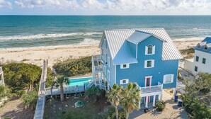 A two-story house with a blue exterior, a pool, and a view of the ocean. - Welcome to Beachfront Benefits! (St. George Island)