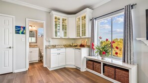 A kitchen with white cabinets, a window with a view, and a vase with flowers. - Welcome to Beachfront Benefits! (St. George Island)