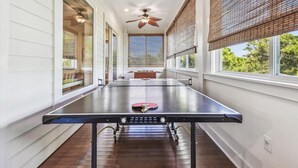 A ping pong table in a room with large windows, ceiling fans, and blinds. - Welcome to Sandy Bottoms! (St. George Island)