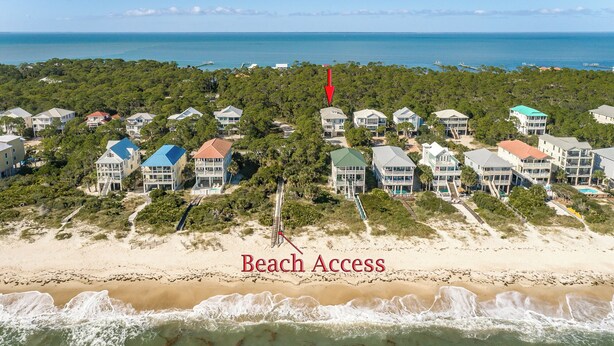 An aerial view of a coastal resort with beachfront properties, a clear view of the ocean, and a marked beach access point. - Welcome to Sandy Bottoms! (St. George Island)