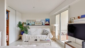 Una sala de estar moderna con un sofá blanco, una mesa de centro, un televisor y una estantería.