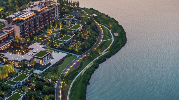 An aerial view of a modern hotel with multiple buildings, a landscaped garden, and a waterfront promenade. - Four Seasons Hotel Suzhou (Suzhou)