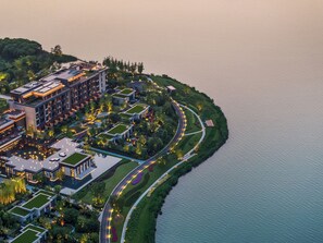 An aerial view of a modern hotel with multiple buildings, a landscaped garden, and a waterfront promenade. - Four Seasons Hotel Suzhou (Suzhou)