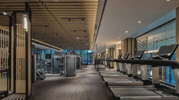 A gym with treadmills, weight machines, and a wooden floor.