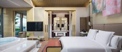 A modern hotel room with a large bed, a separate bathroom, a TV, and a hot tub.