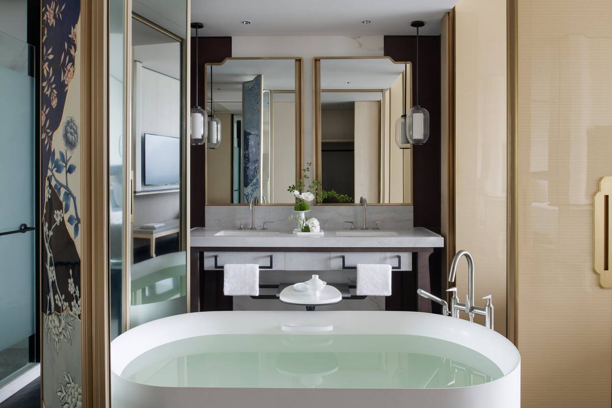 A modern bathroom with a freestanding bathtub, dual sinks, and a large mirror.