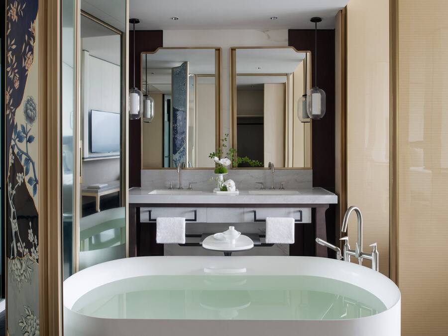 A modern bathroom with a freestanding bathtub, dual sinks, and a large mirror.