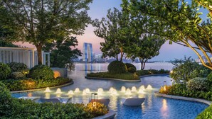 A landscaped pool area with fountains, seating, and a view of a city skyline. - Four Seasons Hotel Suzhou (Suzhou)