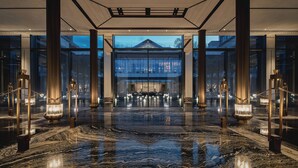 A spacious lobby with a reflective marble floor, large glass doors leading to a reception area, and tall columns with lighting fixtures. - Four Seasons Hotel Suzhou (Suzhou)
