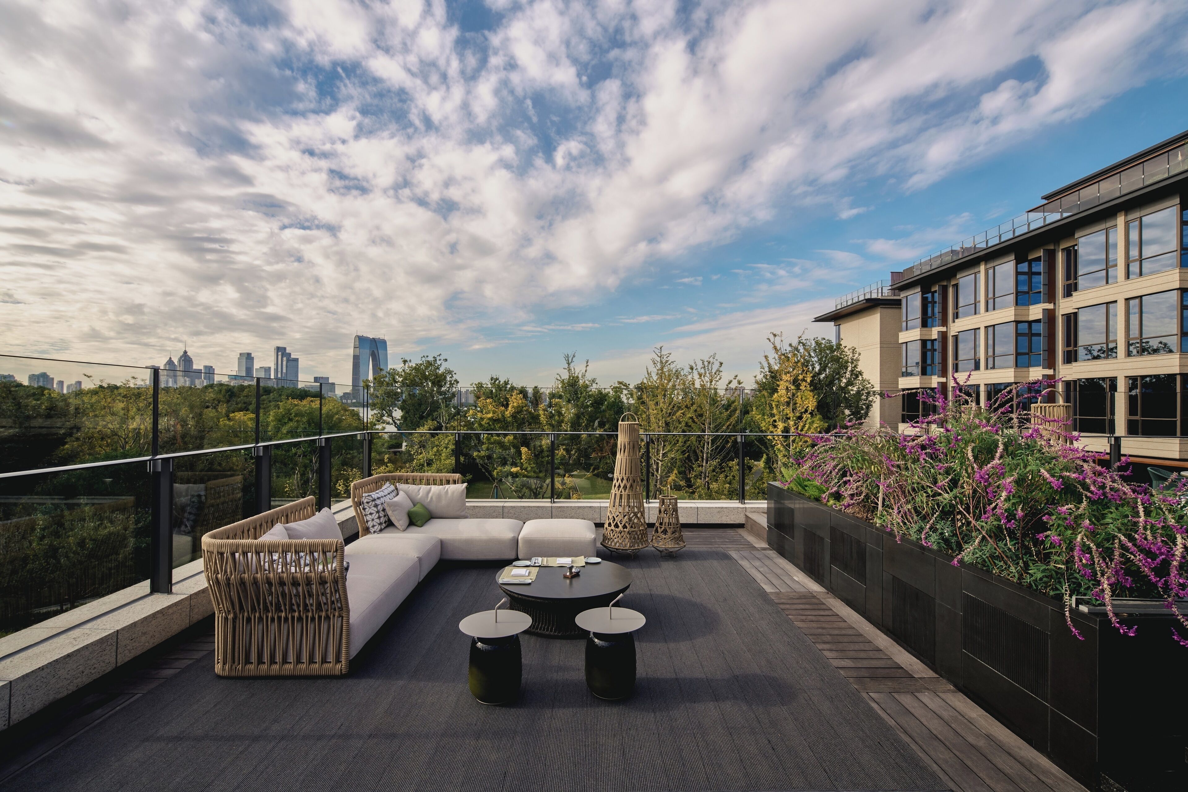 Una terraza en la azotea con un conjunto de sofás, dos mesas redondas y vistas del horizonte de la ciudad.