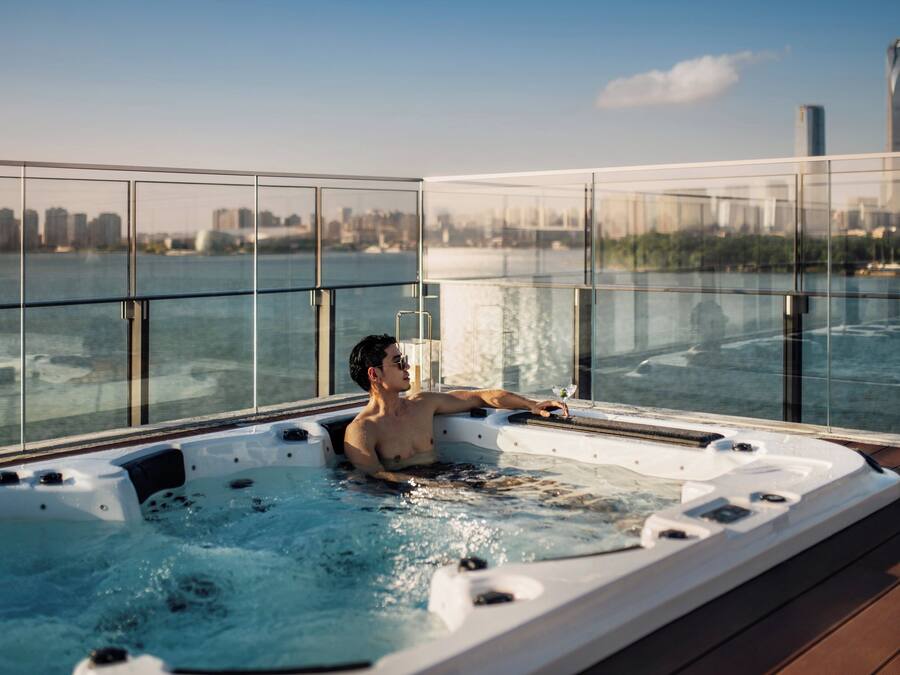A man relaxing in a hot tub with a city skyline view.