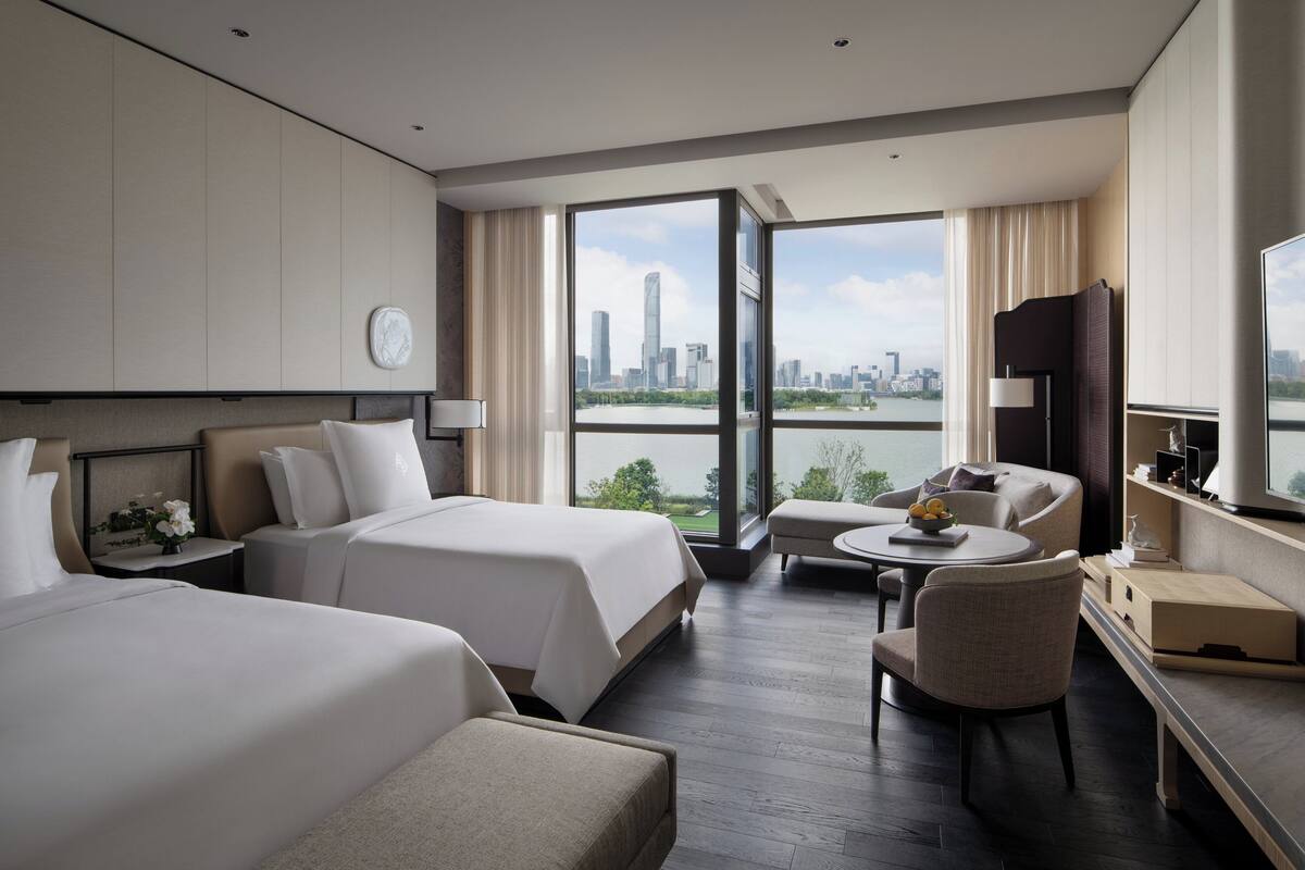 A hotel room with two beds, a sofa, a small table, and a TV.