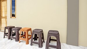 Four stools in front of a building with a wooden door and a window. - OYO 92541 Suny Kost Syariah (Sidoarjo)